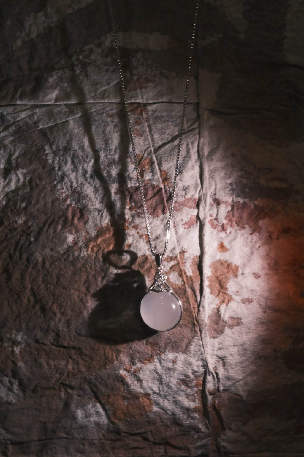 Necklace with a round pendant on a textured stone surface