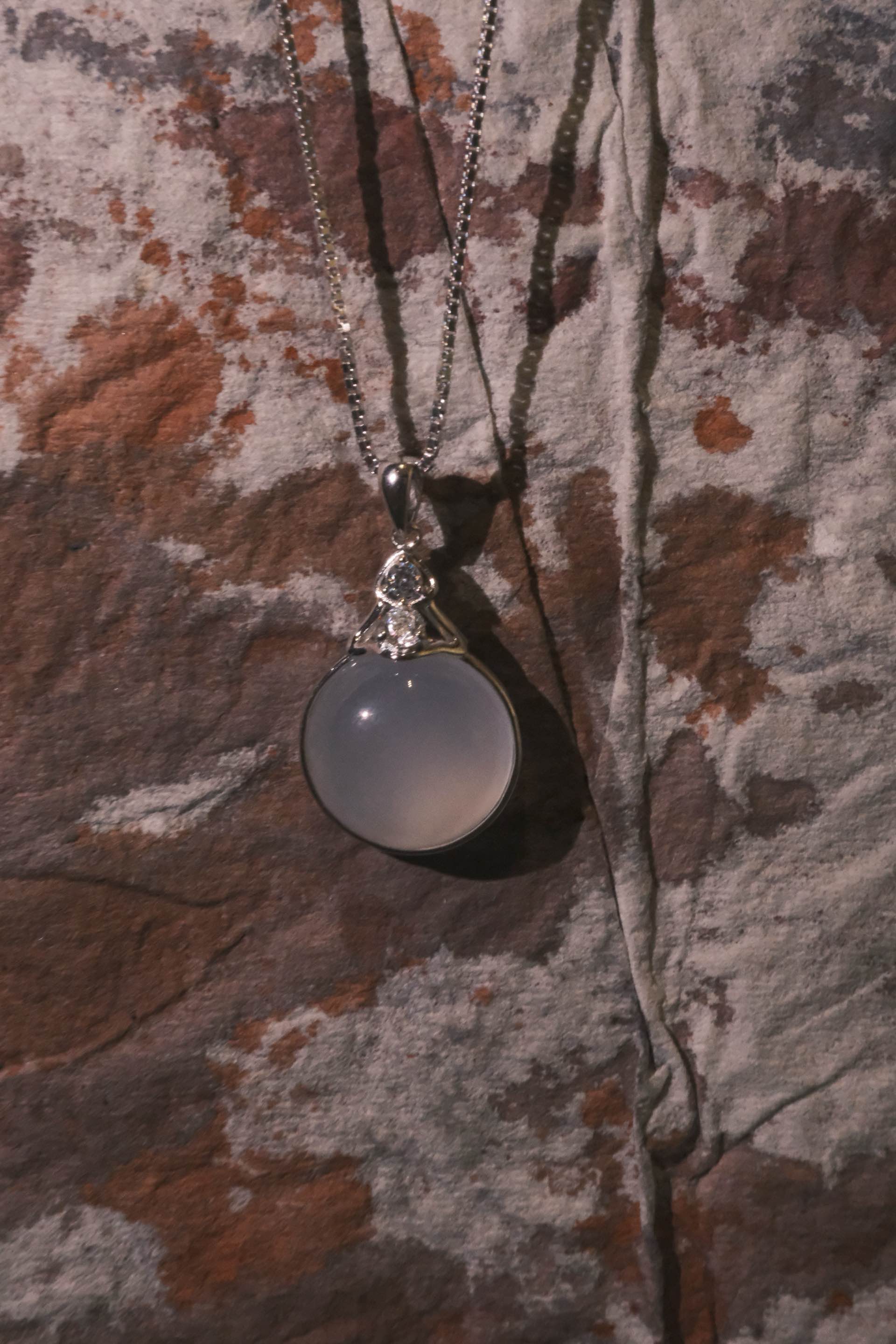 Necklace with a round pendant on a textured fabric background
